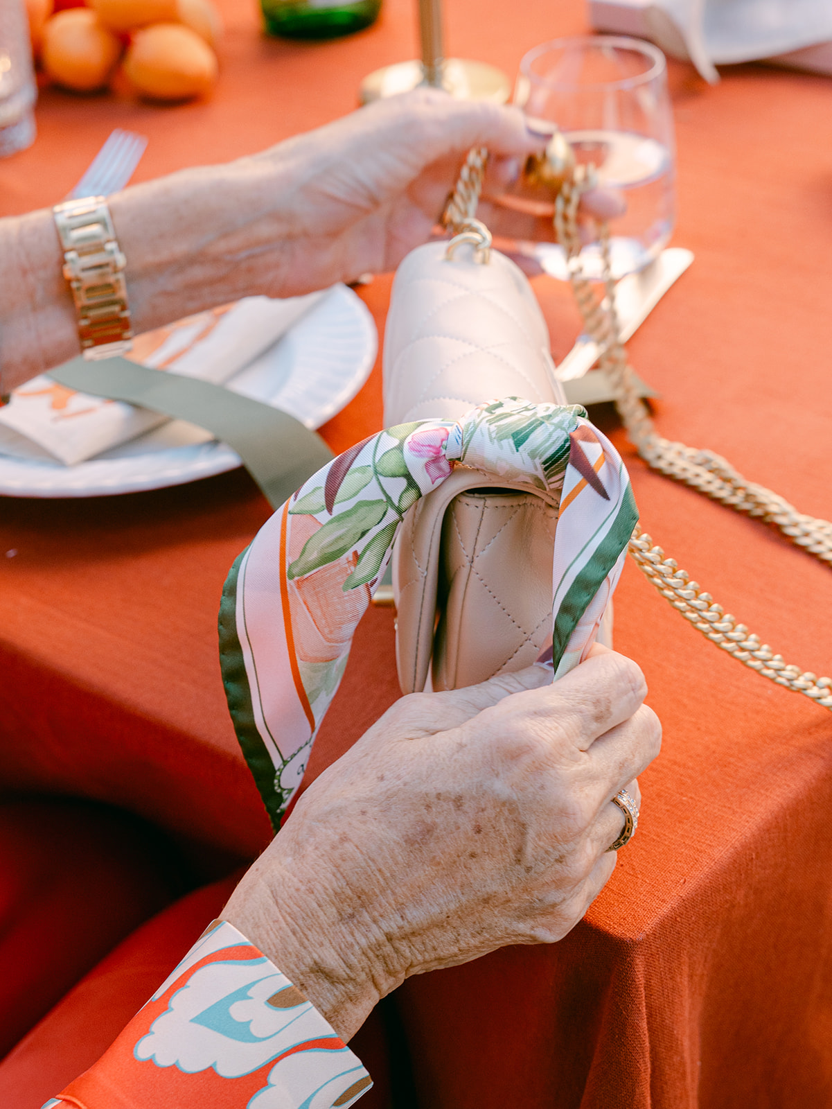 A By Biehle custom silk pocket square tied onto a guest's quilted handbag at a wedding dinner table