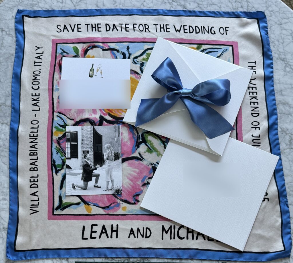 A silk save-the-date for a Lake Como wedding, the venue and the couple's names printed in the border, with its envelope and blue bow